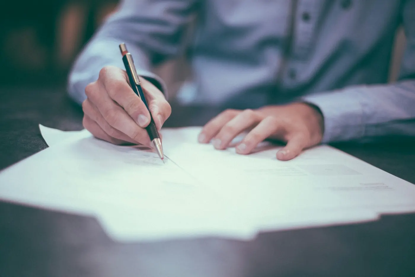 Manos revisando contratos y documentos en un escritorio